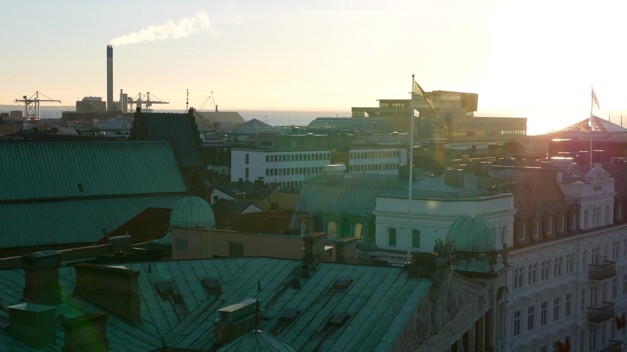 View of city buildings rooftops at sunset. Helsingborg cityscape, Sweden. Smokestack in the background
