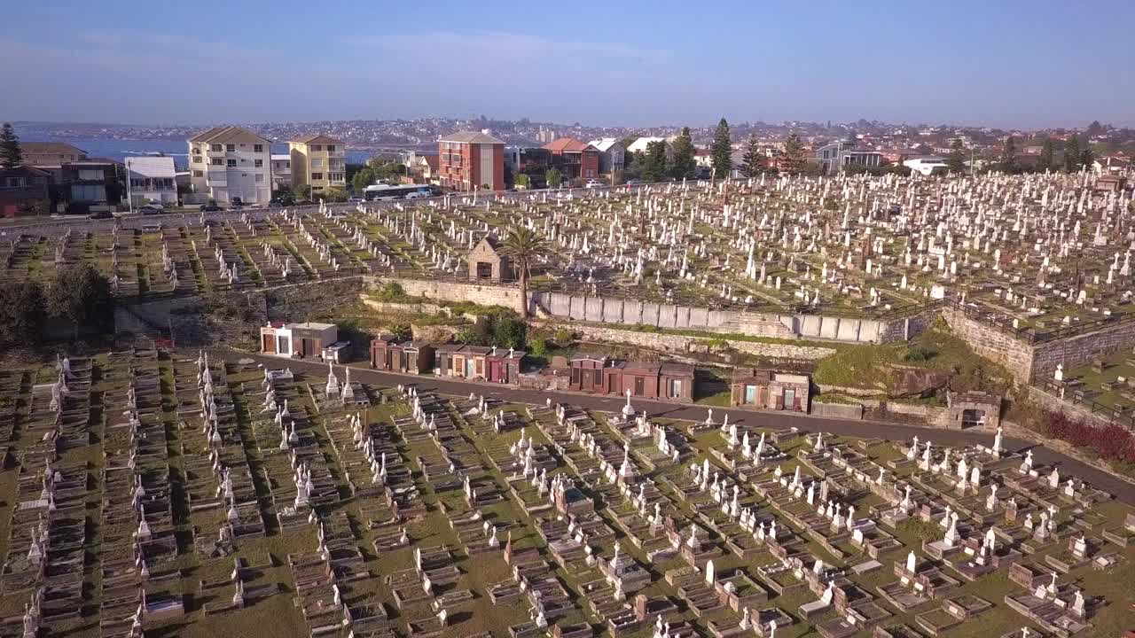 Flying over green cemetery in the suburb of Australia with construction project in the scene, reverse shot.