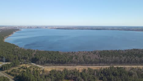 gorgeous high altitude aerial drone footage view of ülemiste lake or ülemiste järv during a sunny day. the lake is a water reservoir to tallinn city and is surrounded by gorgeous pine forest, roads.