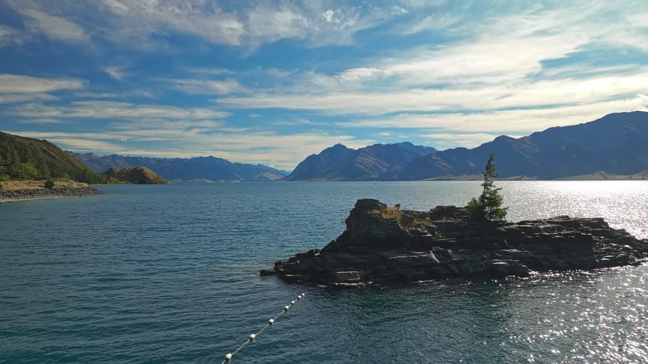섬을 향하는 부이 라인을 따라 공중 도리 (aerial dolly) 는 뉴질랜드의 아름다운 하웨아 호수를 드러니다.