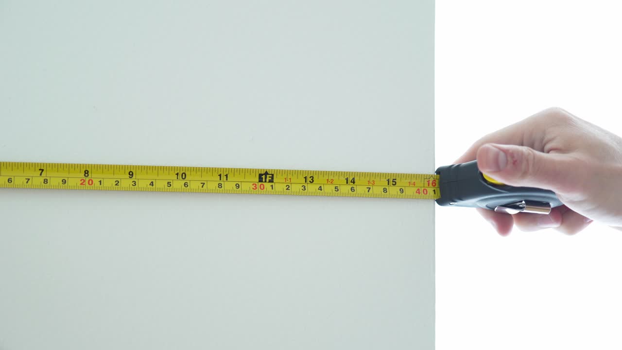 물건 을 측정 하기 위해 측정 테이프 를 사용 하는 남자 의 손