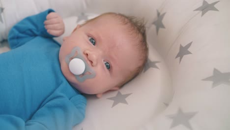 feliz bebé recién nacido chupa muñeco acostado en la cuna con capullo