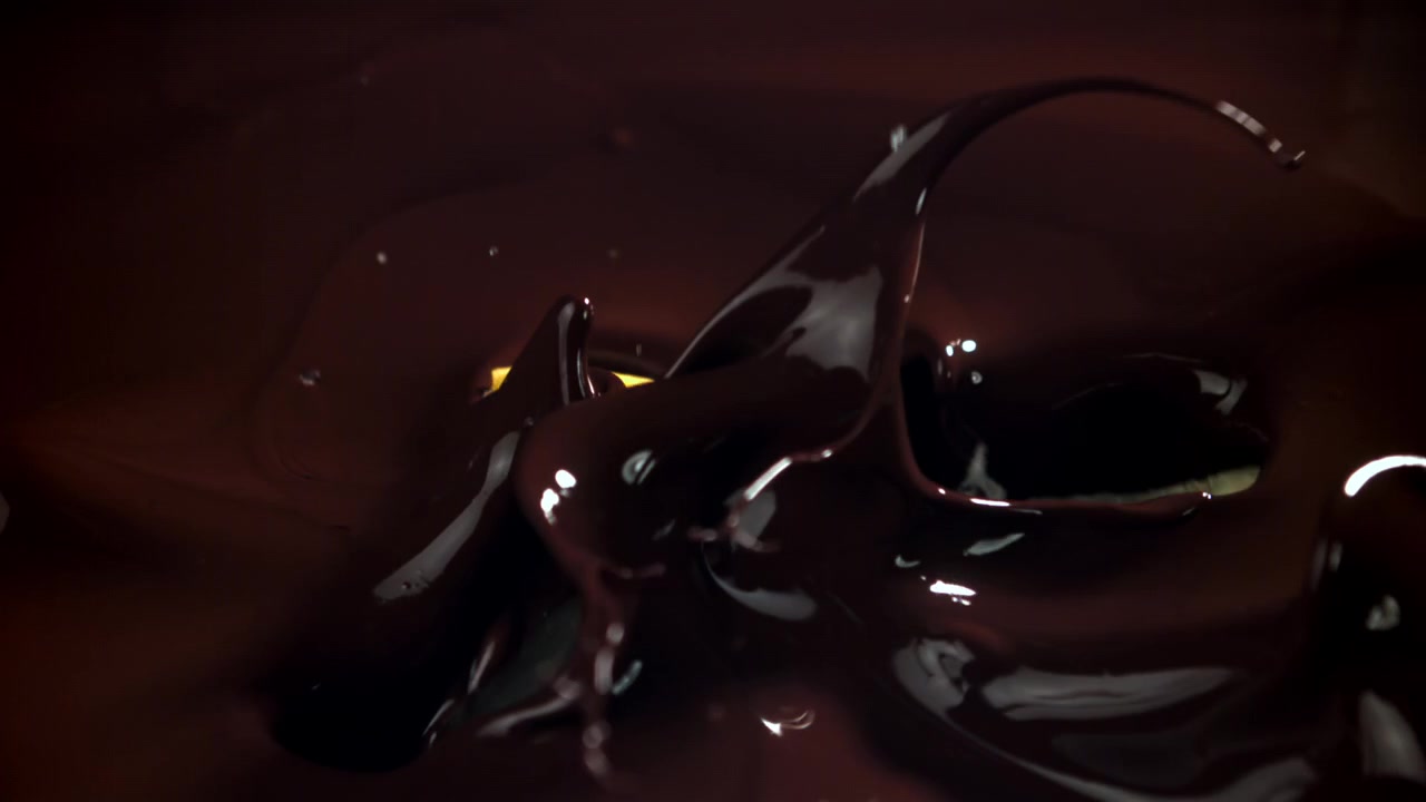 Rodajas de limón cayendo y salpicando en chocolate negro derretido