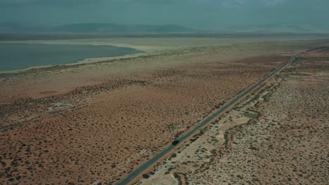 aerial over following behind car travelling along road through desert plains in balochistan