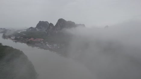 Toma-Aérea-A-Través-De-Nubes-Brumosas-Sobre-La-Sede-Del-Parque-Nacional-Ao-Phang-Na-Con-Vistas-A-Manglares-Y-Acantilados-De-Piedra-Caliza.