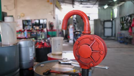 Orange-Hand-Crank-Fuel-Pump-seen-at-an-Auto-Repair-Shop,-Bangkok,-Thailand