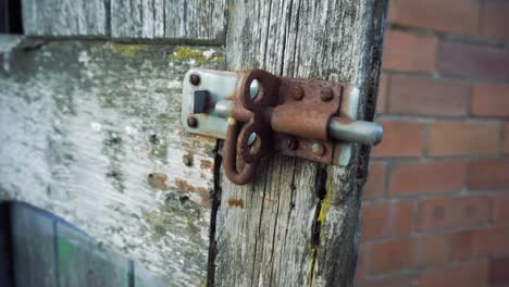 rusting old bolt lock on worn wooden door