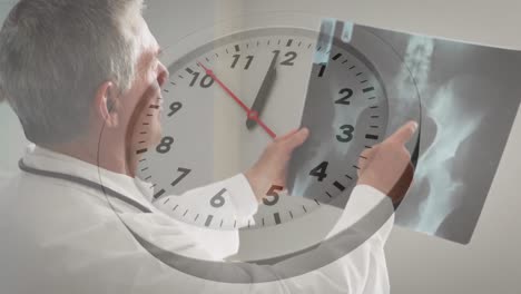 animation of ticking clock against caucasian male senior doctor examining x-ray report at hospital