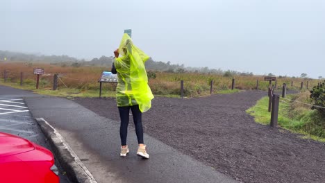 mujer bajo la lluvia en el exterior del borde del volcán mauna loa en hawaii, día nublado