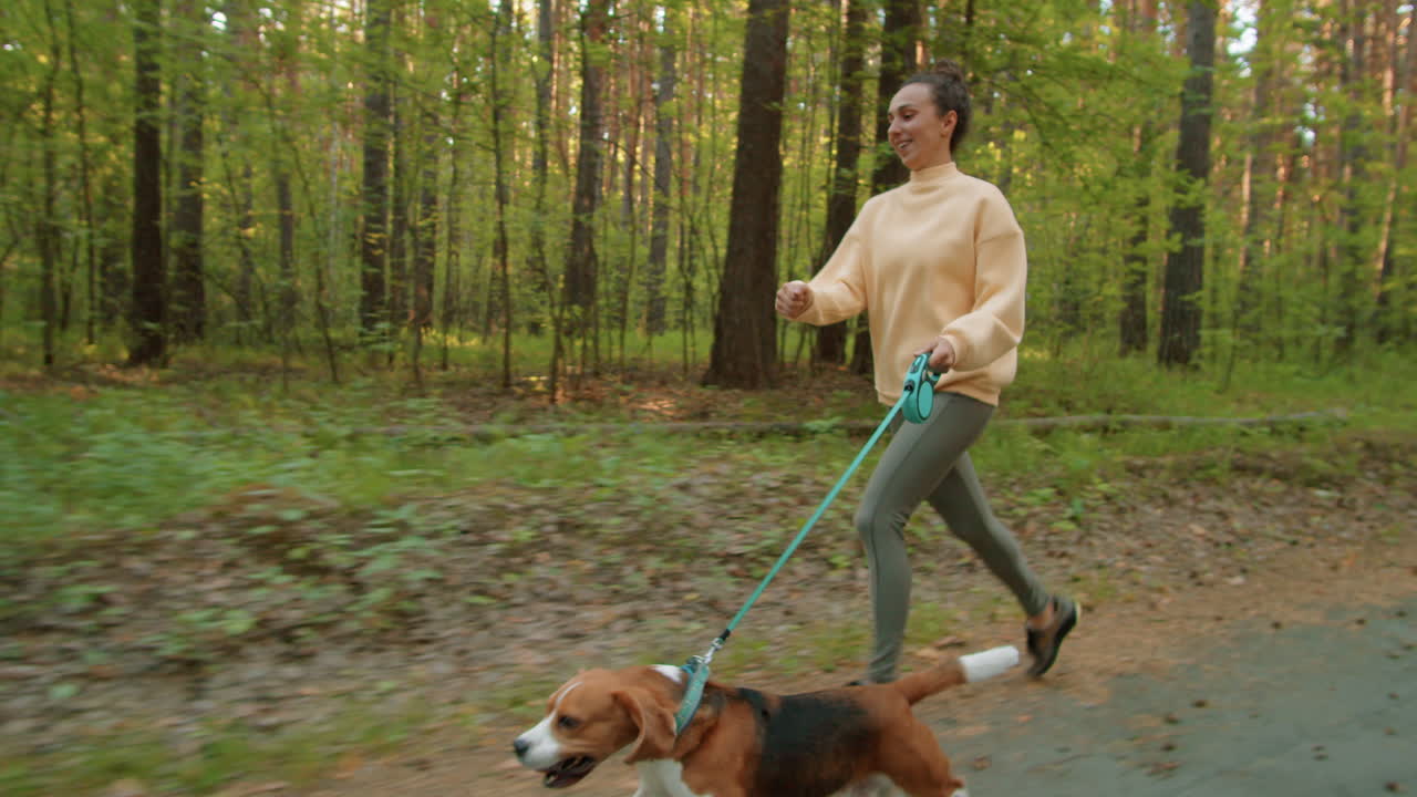 mujer corriendo con un perro beagle en el bosque