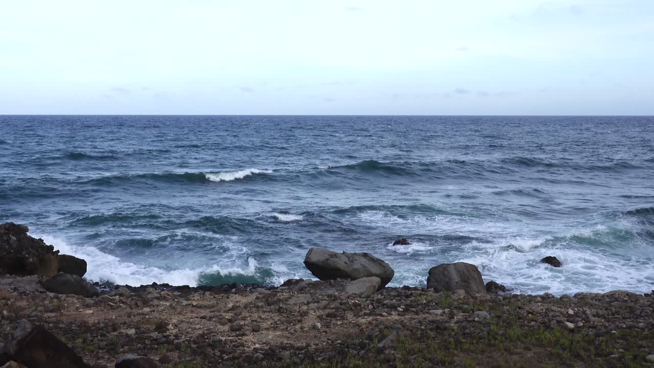해변을 따라 바위에 부서지는 파도가 공중으로 스프레이를 던집니다.