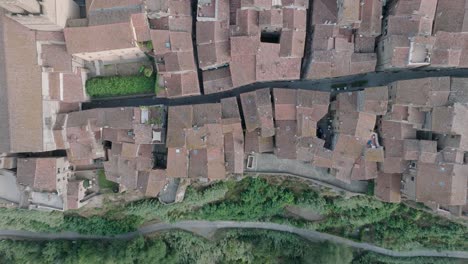 top down aerial drone view of the hilltop medieval town of pitigliano, tuscany in morning light, with red tile roofs and old buildings, in 4k