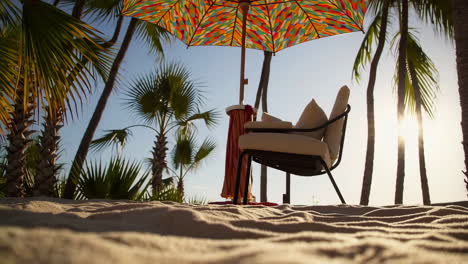 a serene beach scene with a colorful umbrella and lounge chair under palm trees