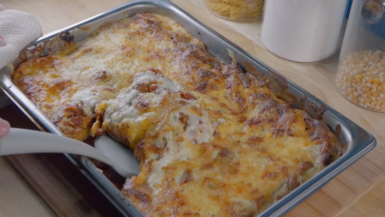 Medium Shot of Using a Spatula to Serve a Portion of Lasagne from the Baking Tray on the Kitchen Counter