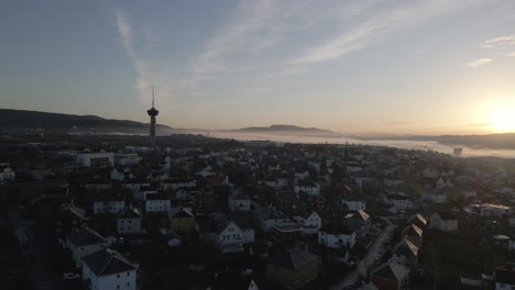 Flying-with-a-drone-towards-the-sunset-in-the-city-of-Trondheim,-Norway