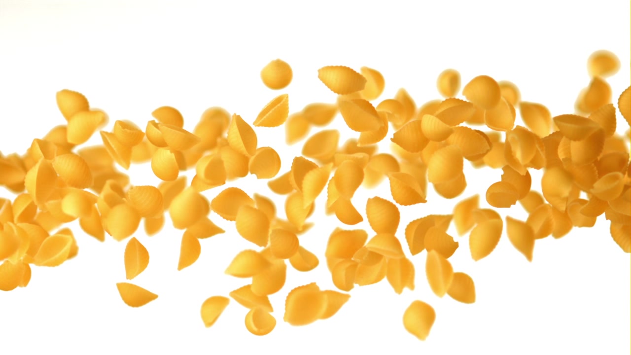 Pasta conchiglie secca che galleggia e cade su sfondo bianco.