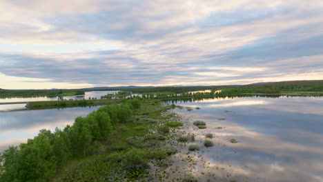 sol de medianoche luz del sol en las nubes que se reflejan en la superficie del lago en la laponia natural, antena