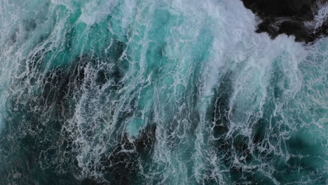 aerial zoom out as ocean waves crash against a rugged coastline