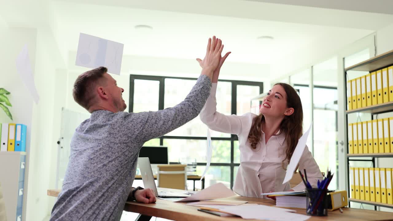 Business colleagues celebrating success by throwing papers in the office