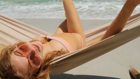 Rear-view-of-Caucasian-woman-relaxing-in-a-hammock-at-beach-4k