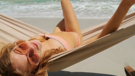 rear view of caucasian woman relaxing in a hammock at beach 4k