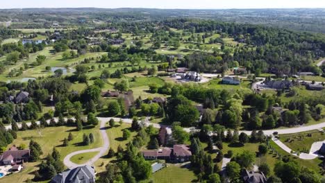 Drone-tilting-up-over-sunny-King-City-neighborhood-filled-with-grass-and-trees