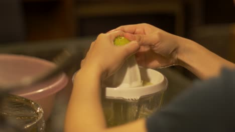jugo de lima extraído de limas verdes frescas por un exprimidor de cítricos eléctrico, filmado sobre el hombro izquierdo como un primer plano medio