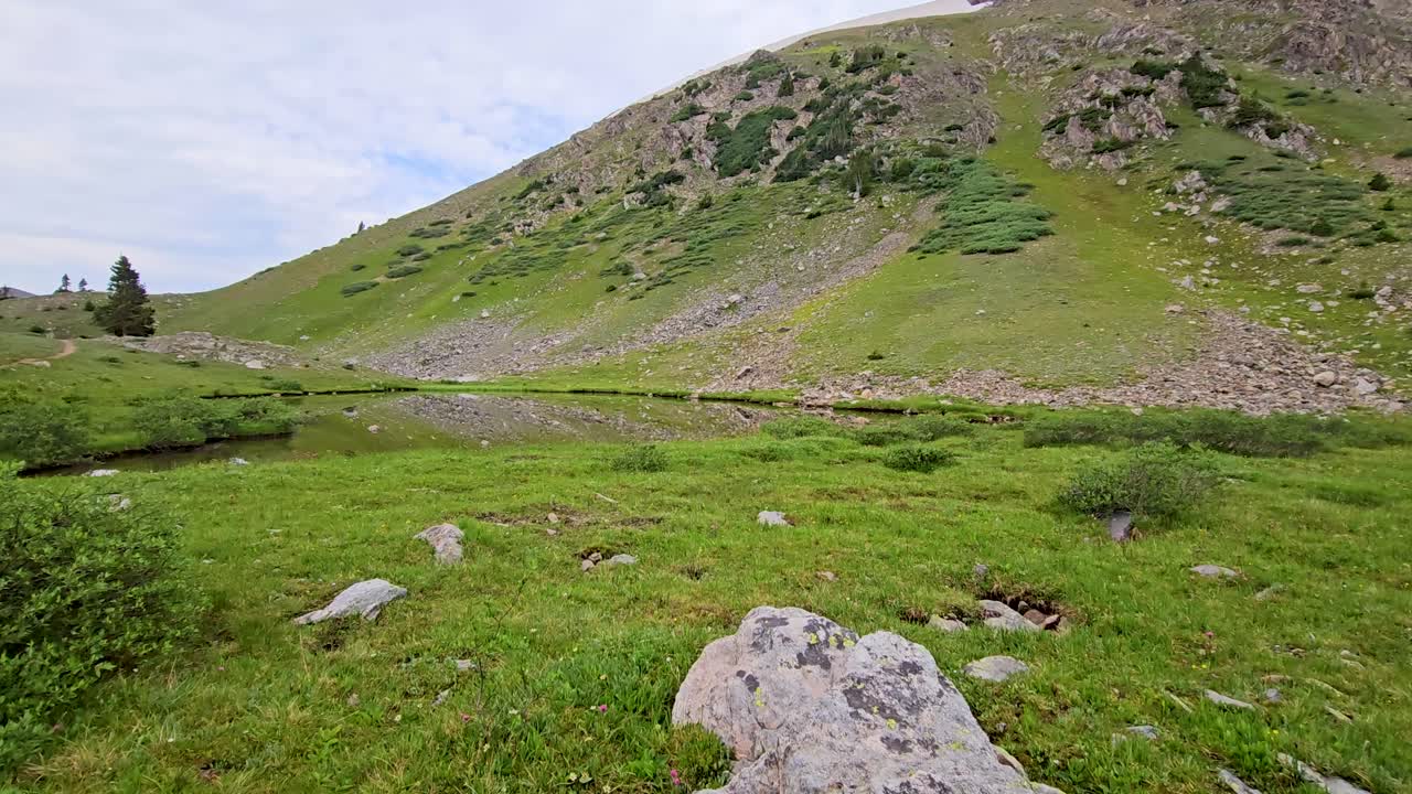 Handheld scenic video of a pond and mountain in Colorado
