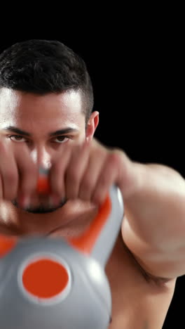 serious muscular man lifting kettlebells