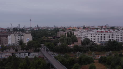 Fly-above-railway-tracks-and-road-bridge-in-city.-Fernsehturm-TV-tower-in-distance.-Berlin,-Germany