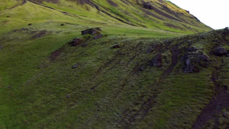 Fpv-Von-Grünen-Hügeligen-Hängen-Mit-Fließendem-Fluss-Bei-Seljavallalaug-In-Südisland