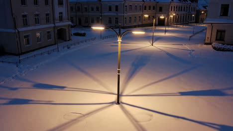 snowy city square at night with long streetlight shadows