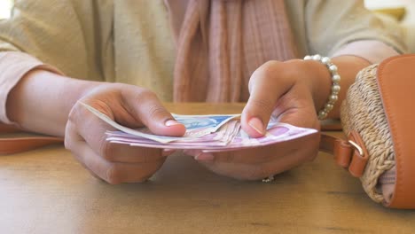 woman counting turkish lira bills at a table