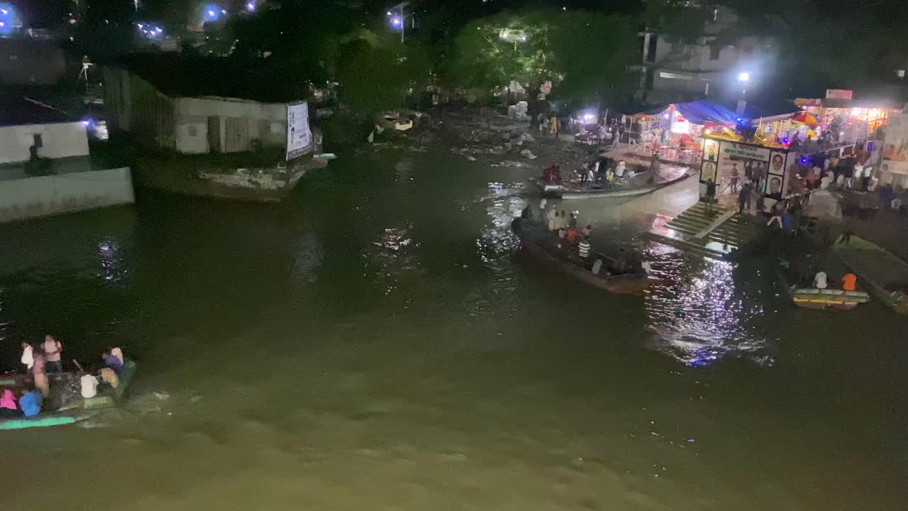 un grupo de hombres con camisas de colores brillantes salen de un muelle cruzando un río por la noche