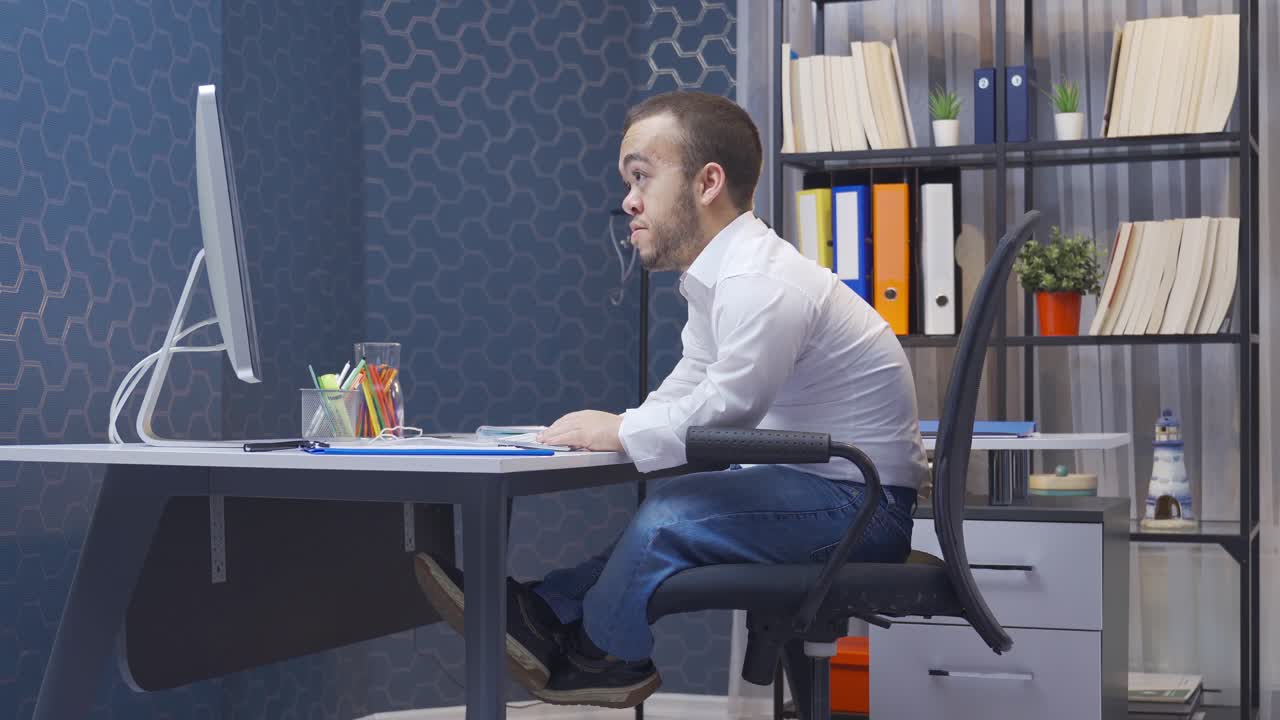 장애인 난쟁이 남자가 컴퓨터에서 기 ⁇ 하고 있습니다.