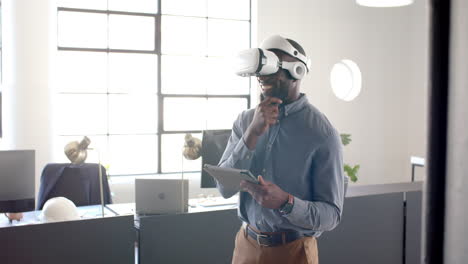 using vr headset, businessman holding tablet and smiling in modern office