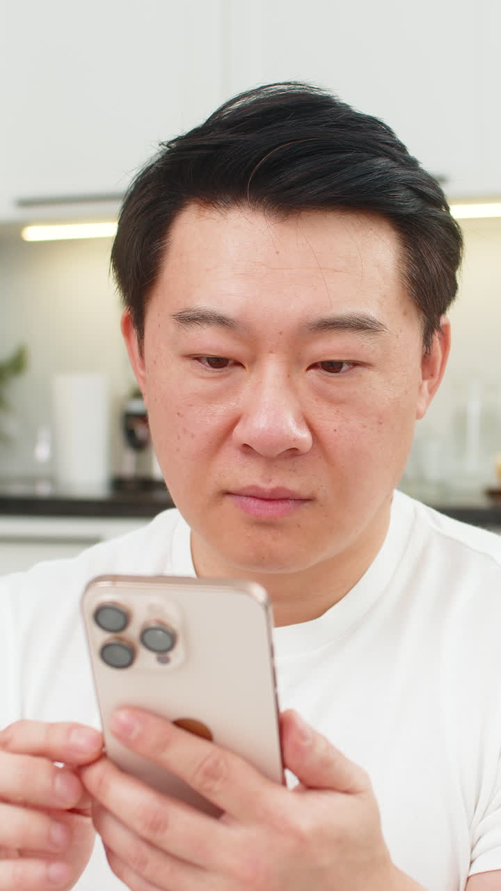 Asian man reads good news on smartphone eyes wide says wow smiles and shares positive update in chat