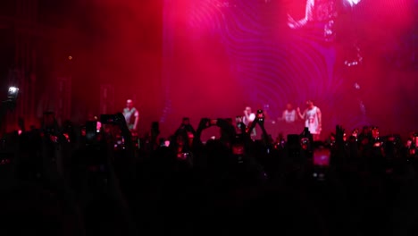 Fans-filming-on-their-smartphones-live-concert-with-singer-performing-on-illuminated-stage