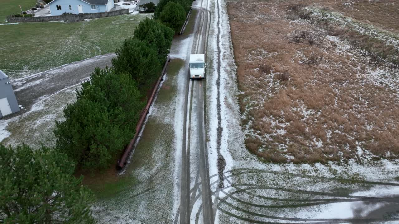 Drone shot of USPS vehicle driving on snow covered rural roads to deliver mail