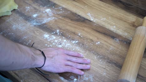 man's hand pouring flour for dough kneading on kitchen counter