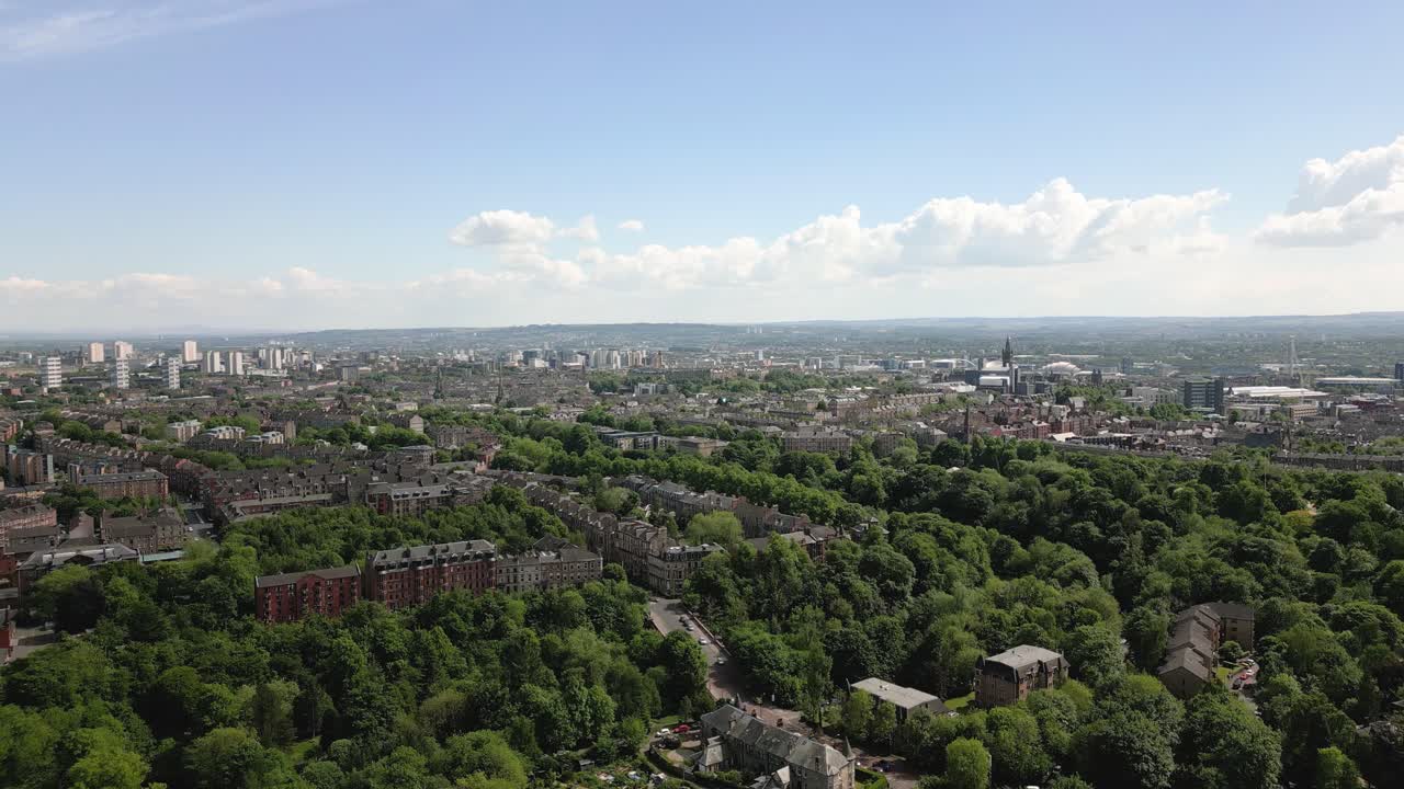 Aerial rise reveal of wide Glasgow Botanic Gardens glasshouses and Glasgow West End in background, Scotland, UK