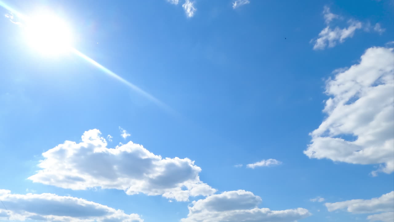 Light white clouds covering the sun from time to time. Cotton puffy cloudscape timelapse.