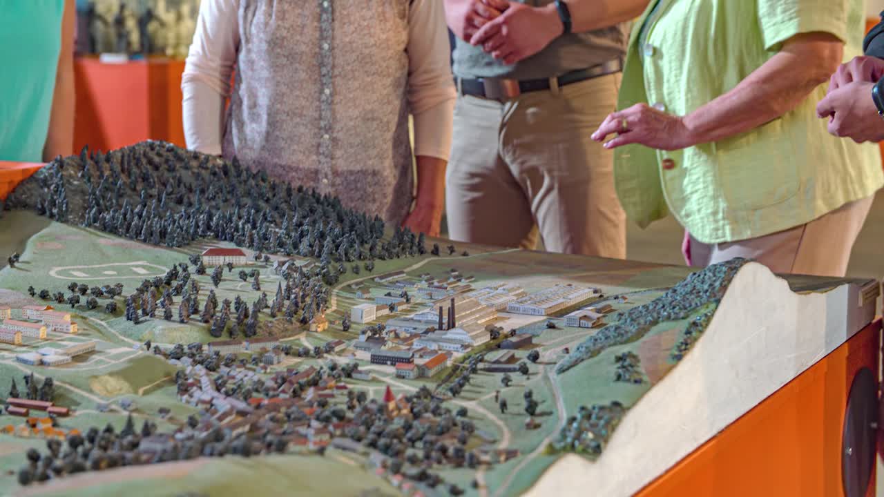 group of people discuss over a scale model of a house development. Tilt down shot