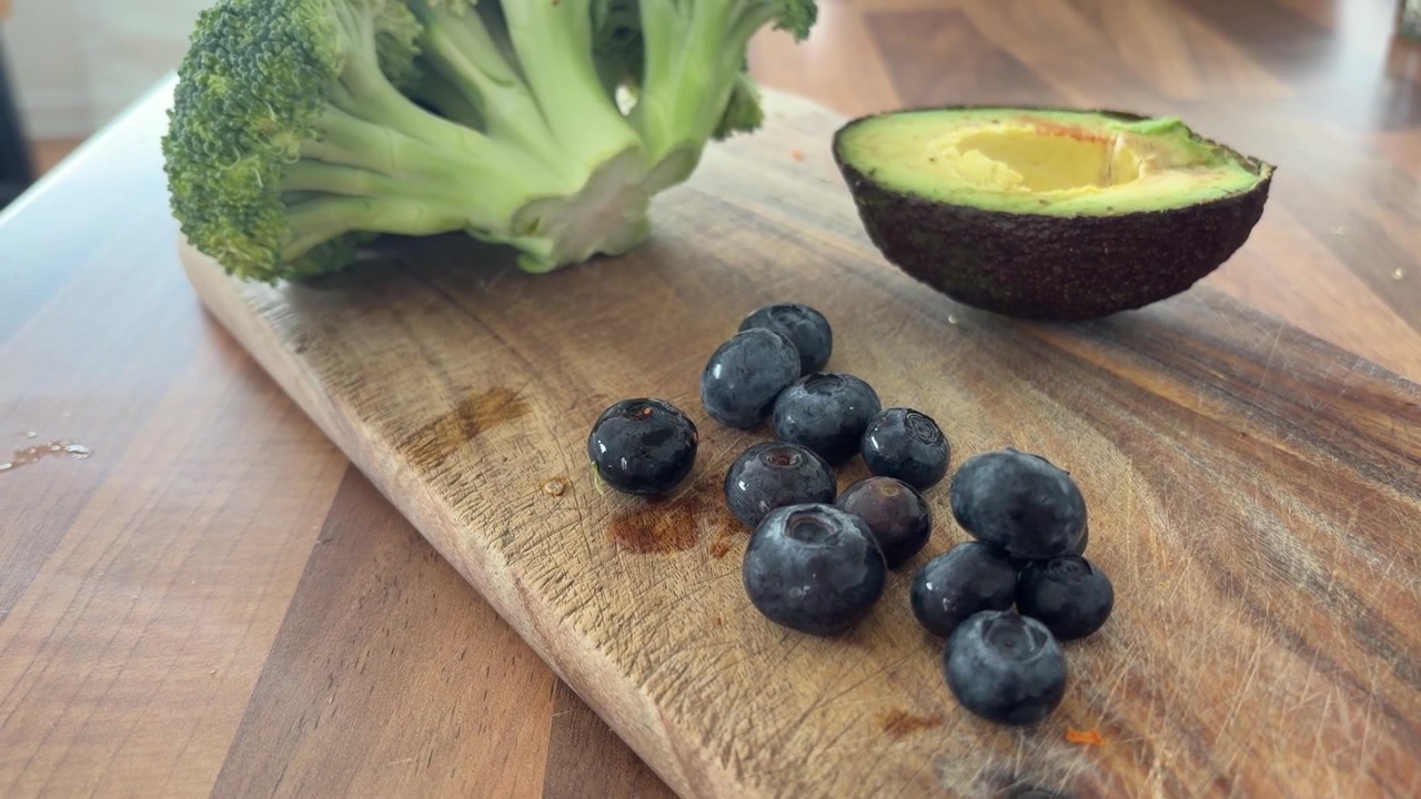 Ingredienti sani con avocado, mirtilli e broccoli su tavolo di legno
