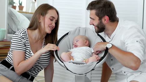 Close---up-of-happy-parents-watching-their-little-baby-sleep-in-a-rocking-chair-for-babies