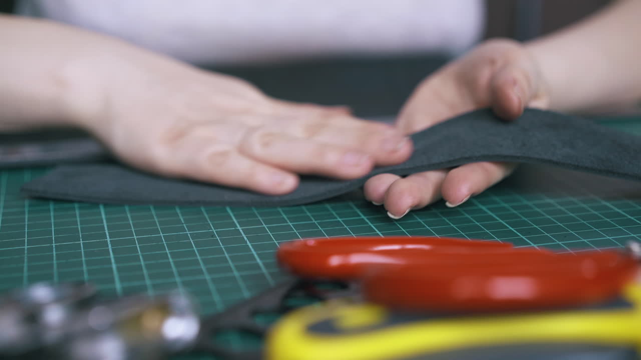 Skilled tailor checks cut leather strip on cushion board