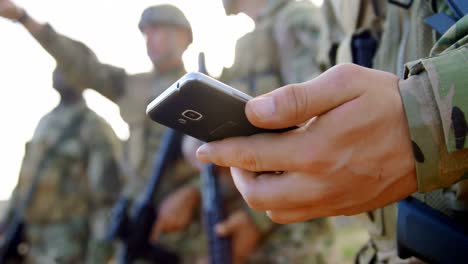 Sección-Media-De-Soldado-Militar-Caucásico-Usando-Teléfono-Móvil-Durante-El-Entrenamiento-Militar-4k