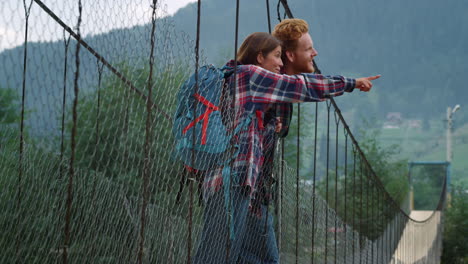 hikers look mountains view landscape. couple backpackers stand on river bridge.