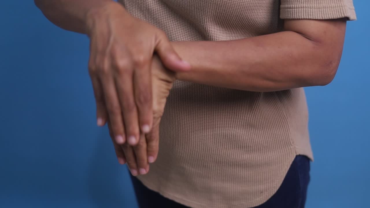 Senior Asian woman rubbing her hands in discomfort, suffering from arthritis in her hand