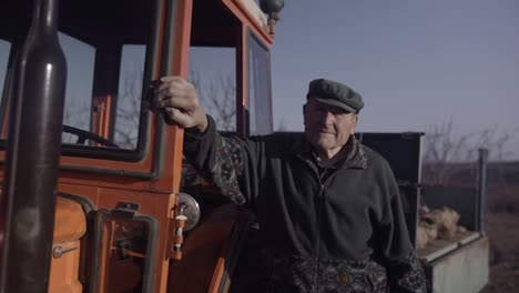 old farmer posing close to tractor cabin